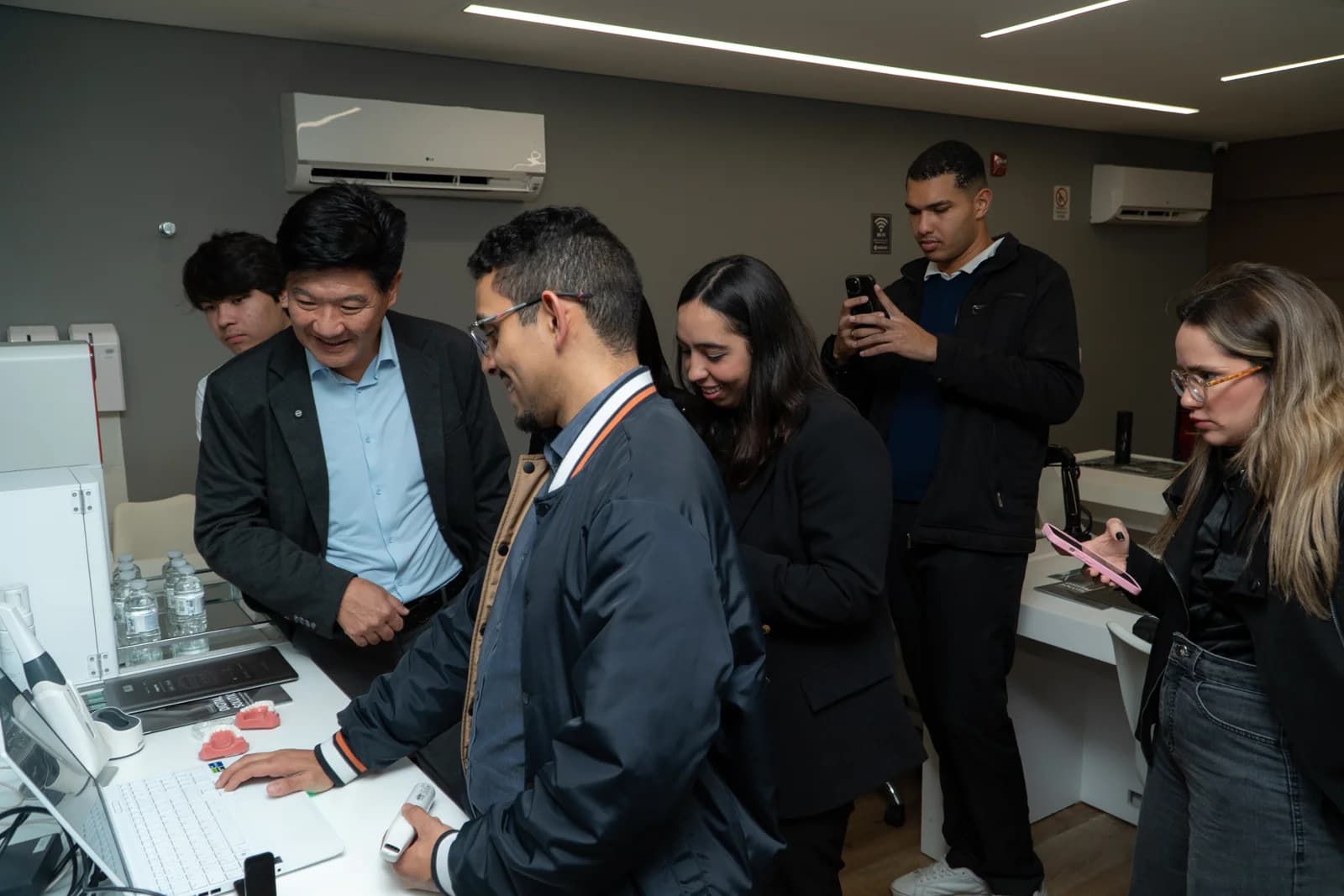 Dr. Rodolfo e participantes reunidos ao redor de uma bancada durante uma demonstração.
