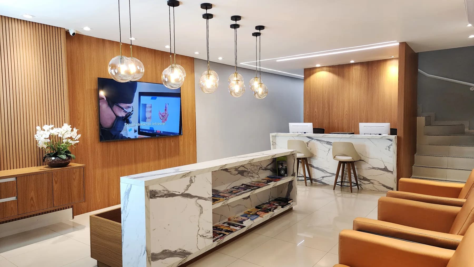 Recepção da Allegra Odontologia com poltronas, balcão em mármore e luminárias suspensas.